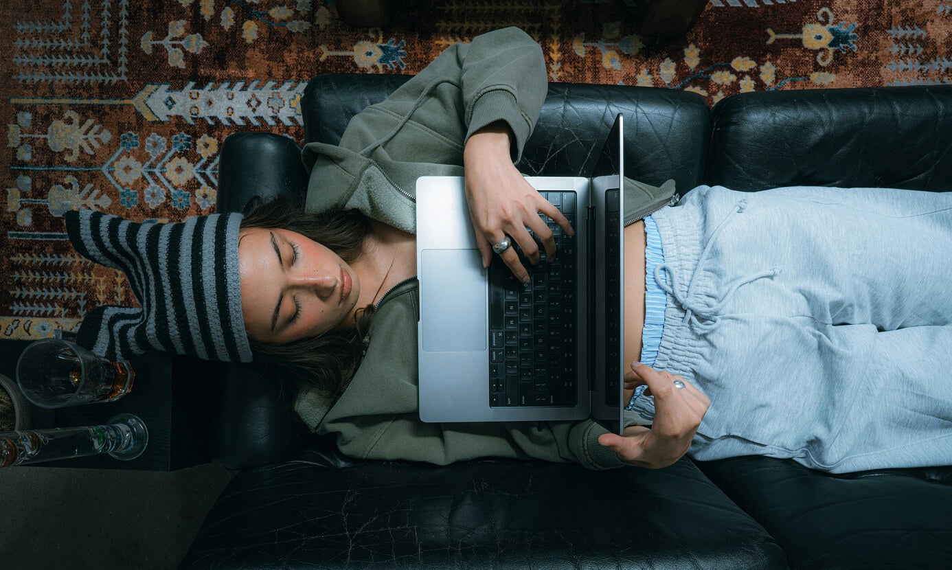 Woman lying on couch with computer