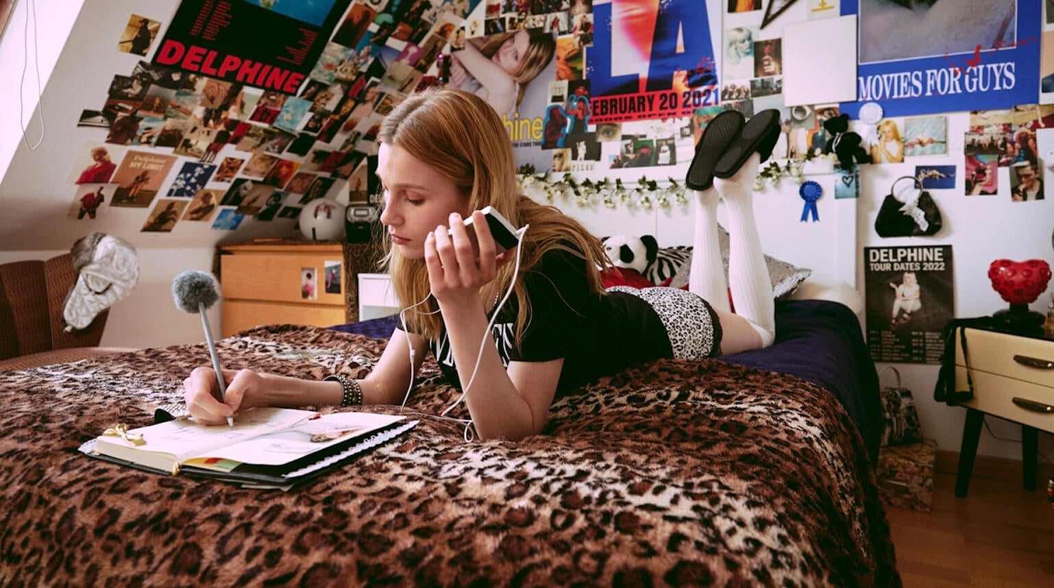 Woman lying on bed writing in book